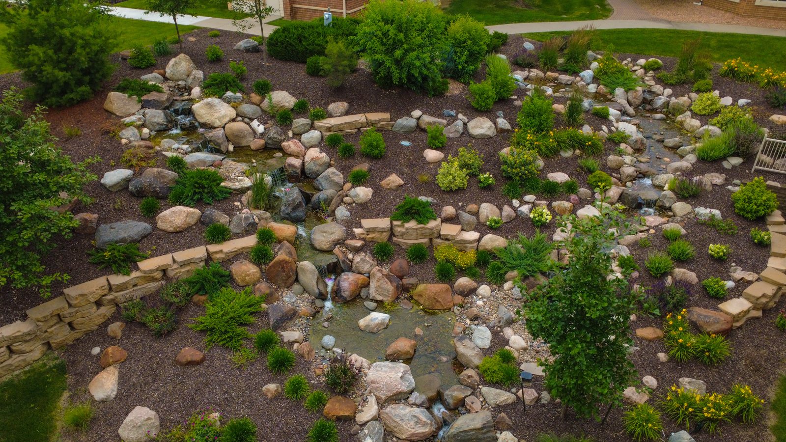 Aerial view of a naturalistic rock stream bed winding through boulders and plantings