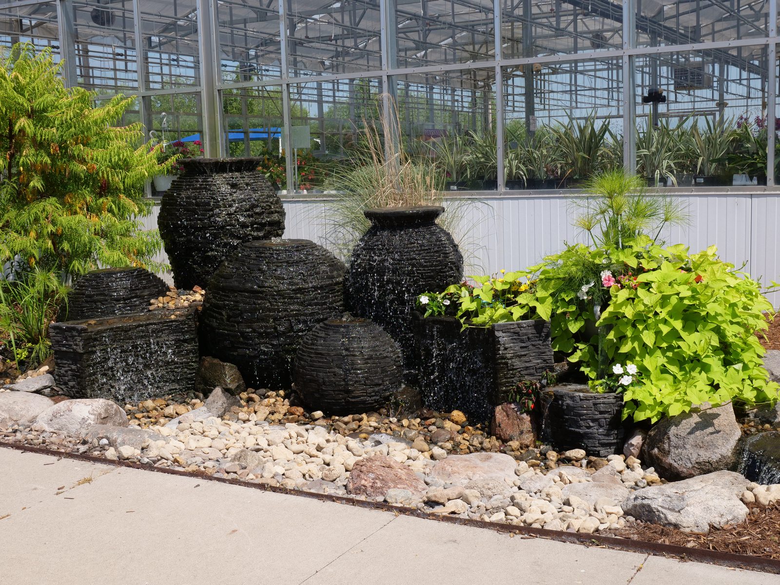 Cluster of black stacked-slate urn and sphere fountains set in river rock