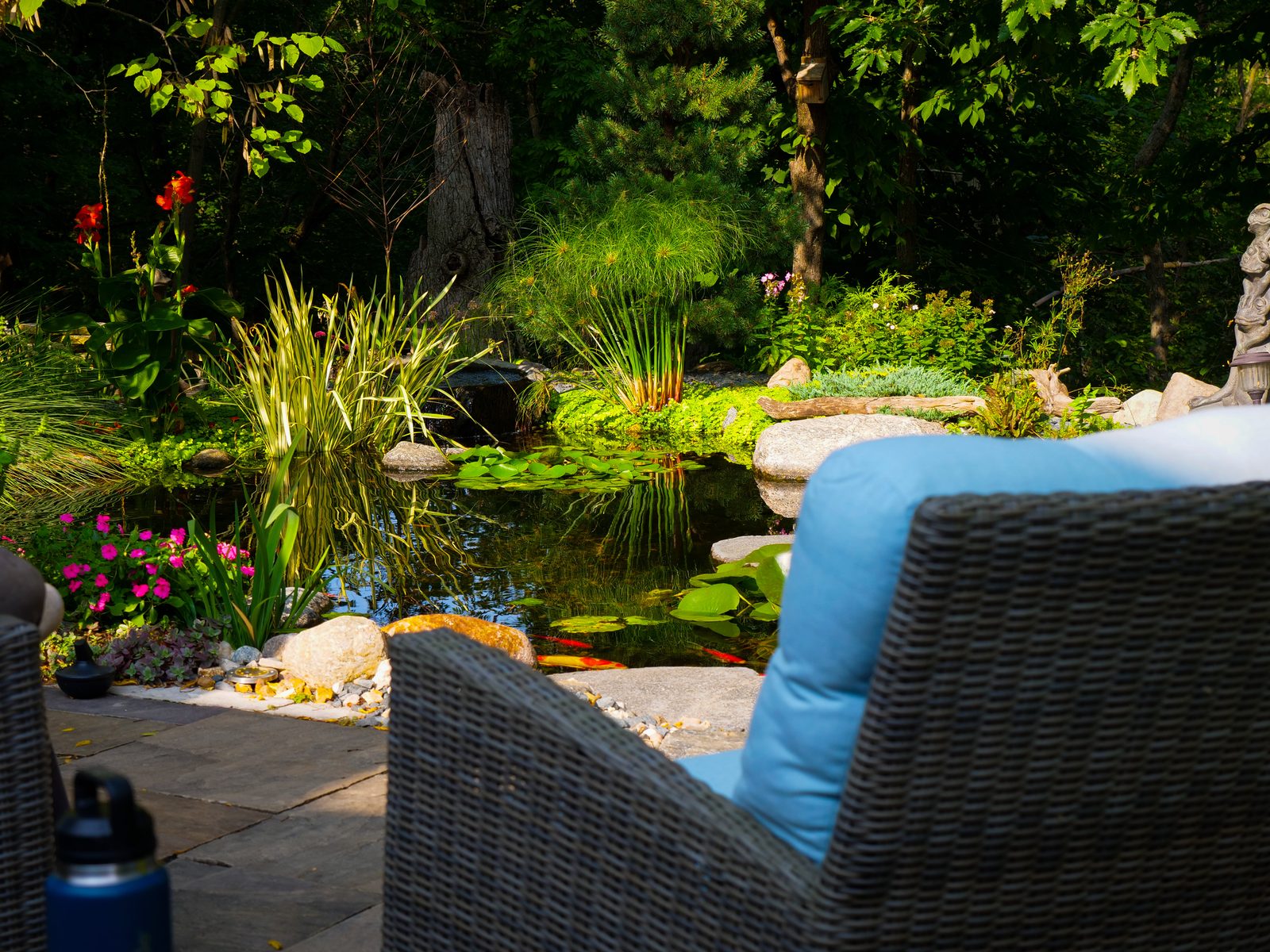 Patio with wicker furniture overlooking a planted pond with water lilies