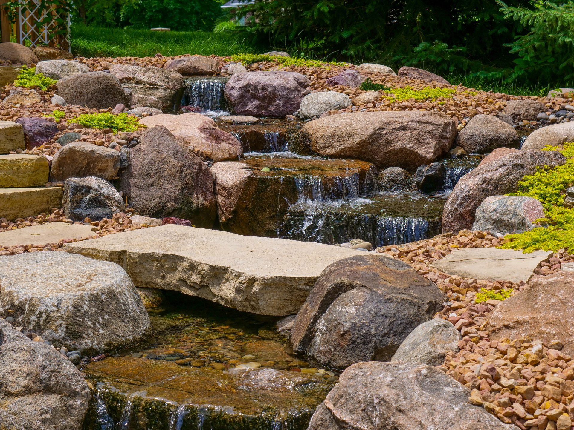 Large backyard waterfall cascading over boulders beside flagstone steps