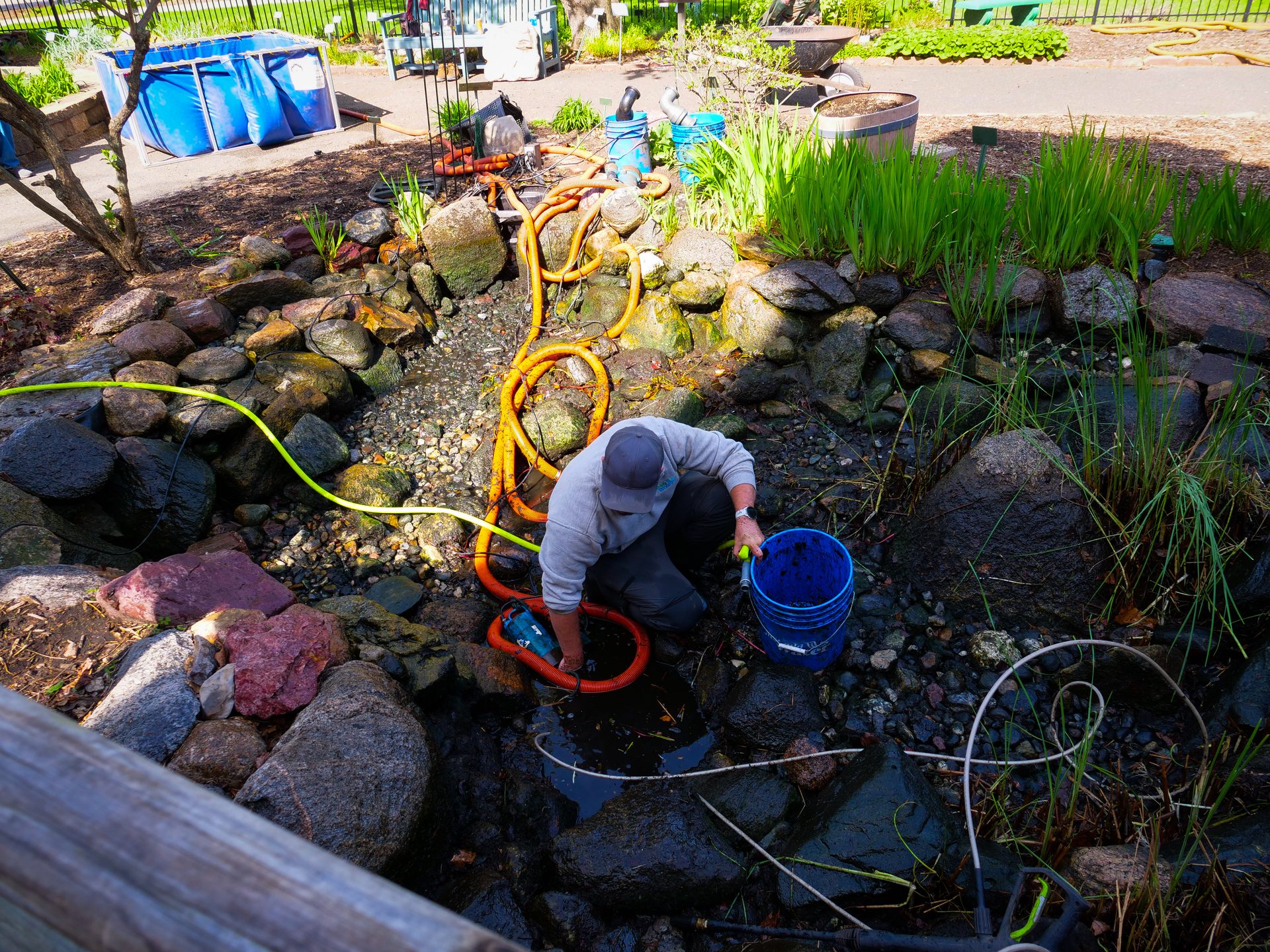 Just Add Water technician performing a pond cleanout with pump hoses and a holding tank