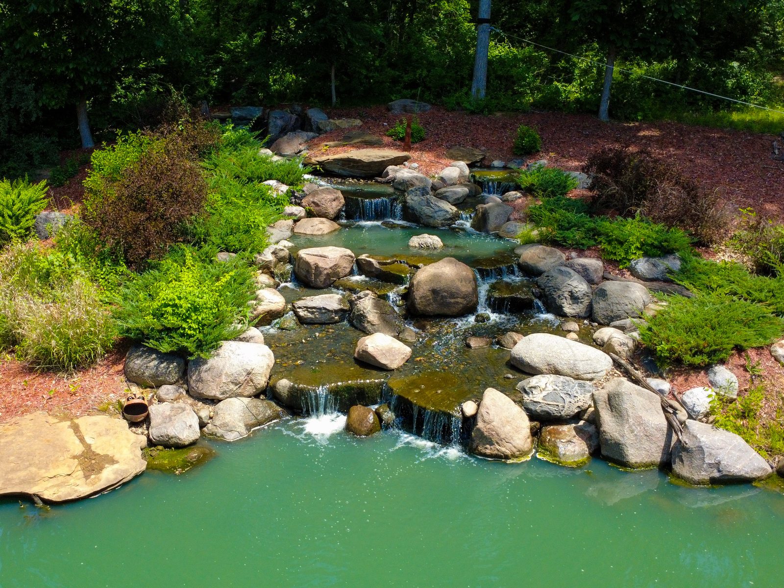 Pond with a layered rock waterfall and boulders
