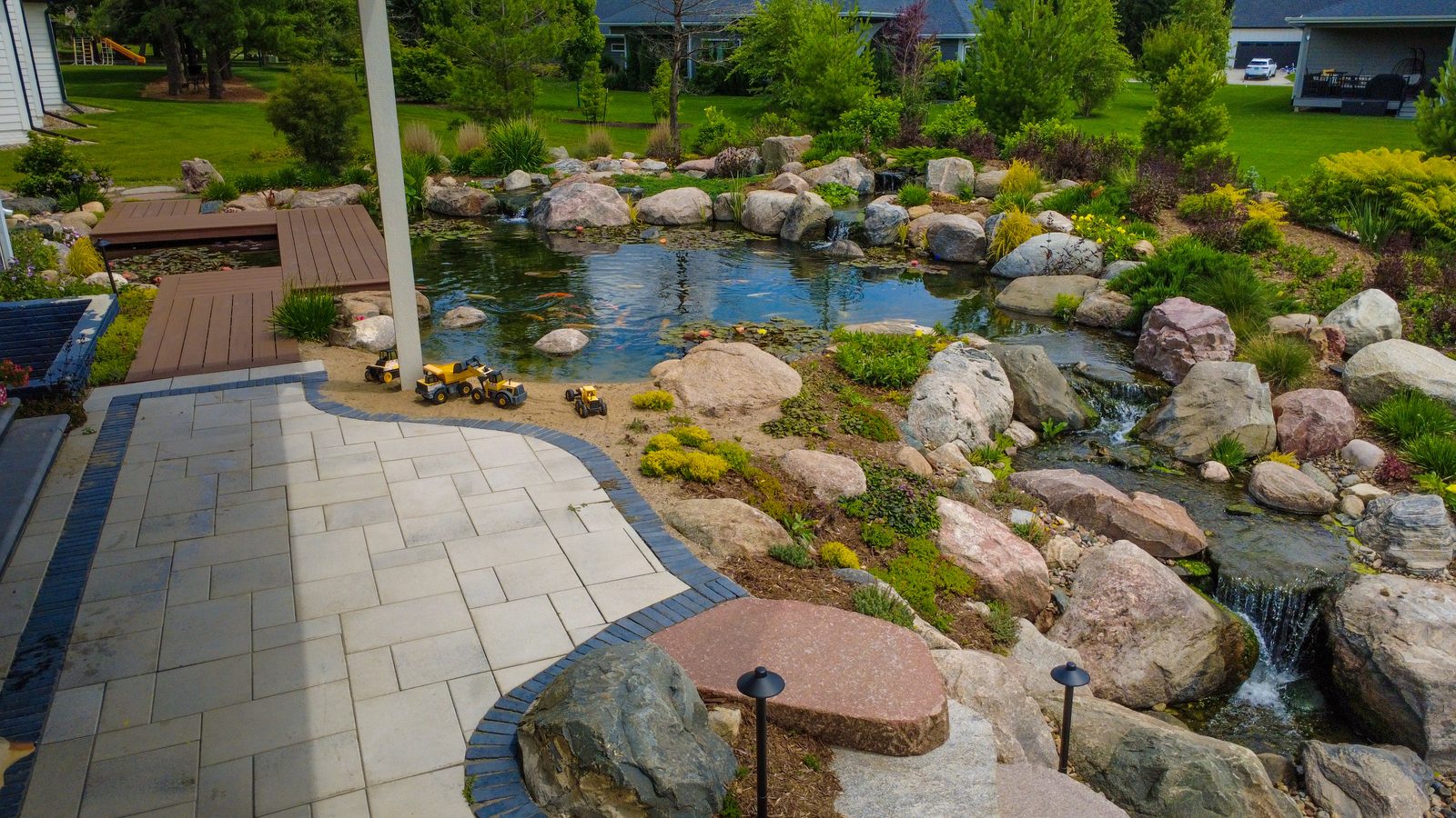 Paver patio and boardwalk beside a landscaped pond